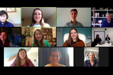 13 people smile at the camera in a video call