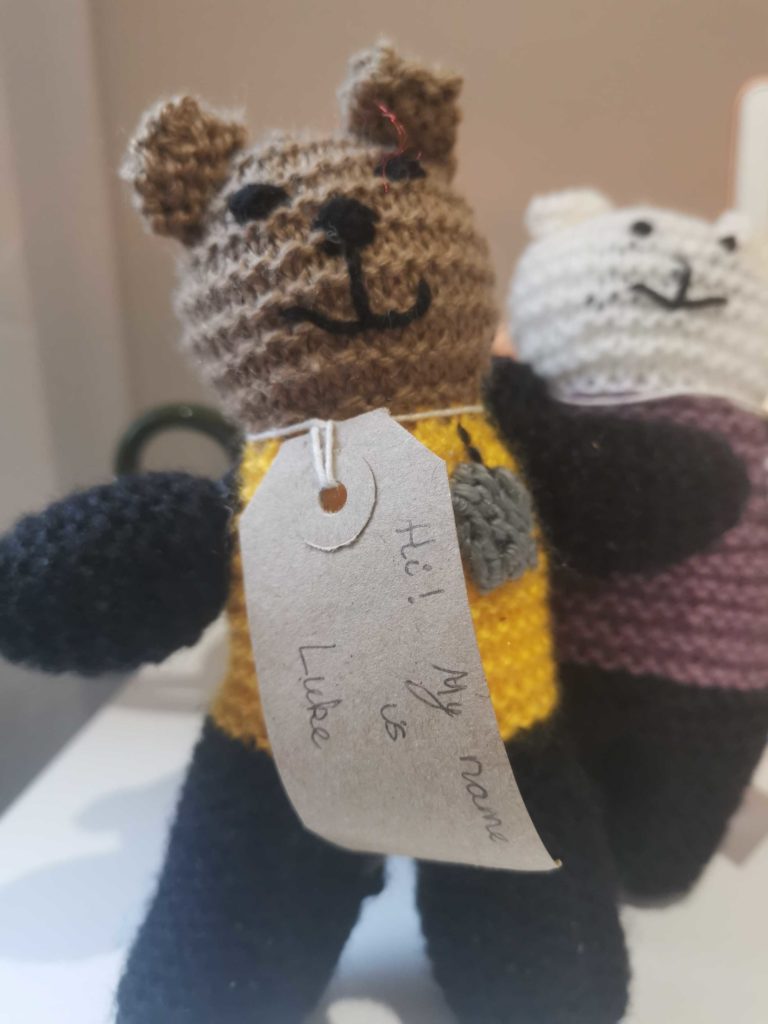 Two knitted teddy bears. One has a label reading "Hi! My name is Luke"