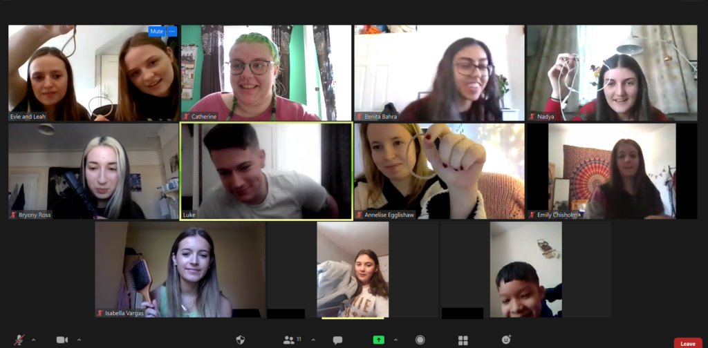 A screenshot shows an online session of Branch Up. 12 people are smiling at the camera holding up items they have found as part of a scavenger hunt. 
