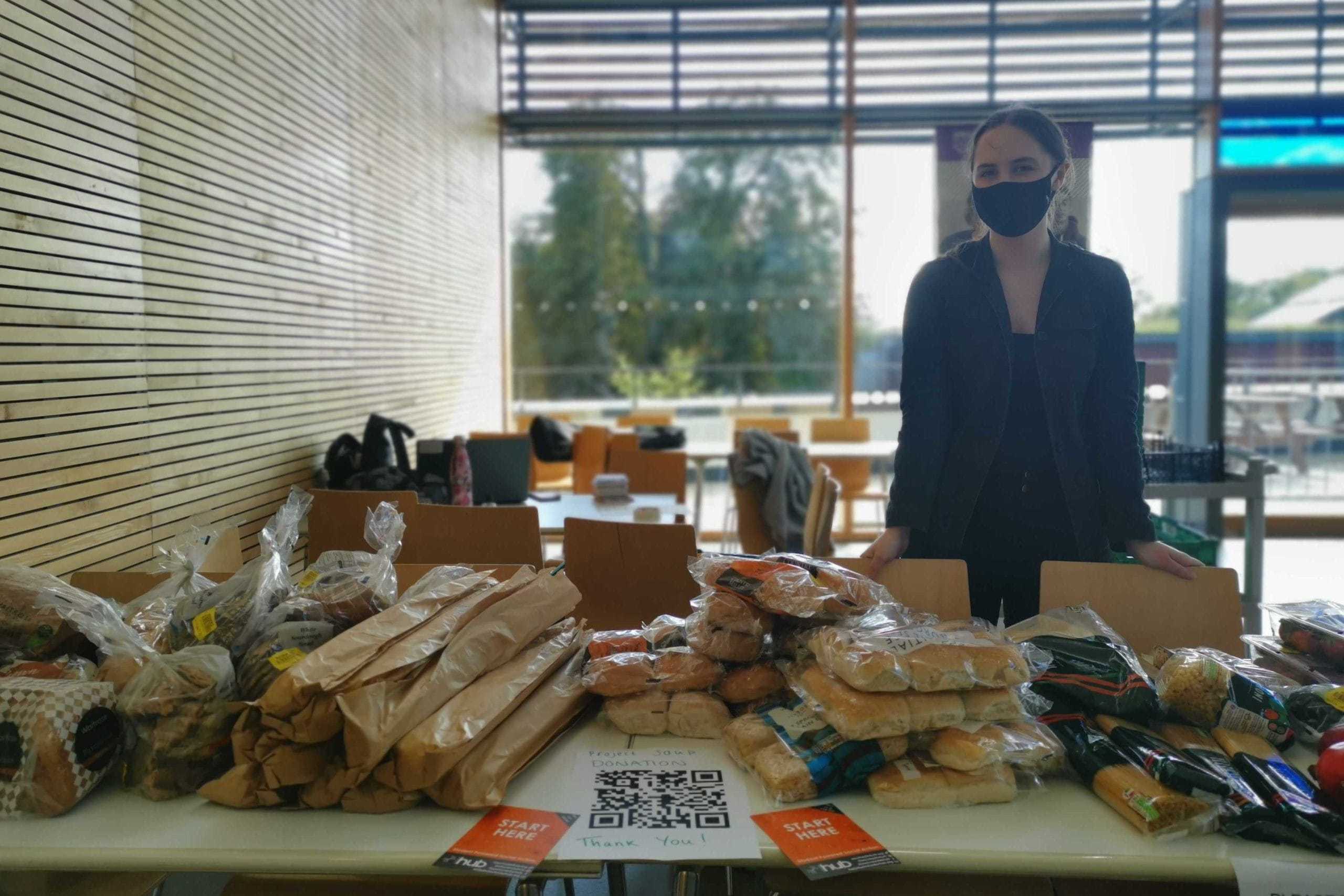 An individual wearing black stands behind a table. The table is covered with bread!