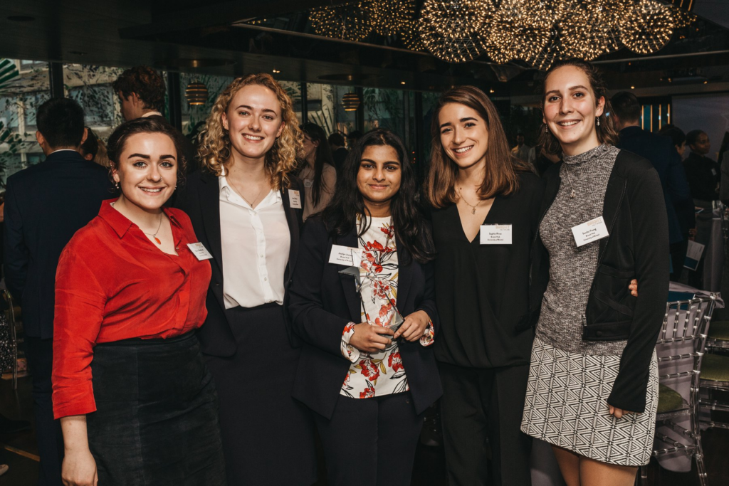 Five students stand in formal wear at an event