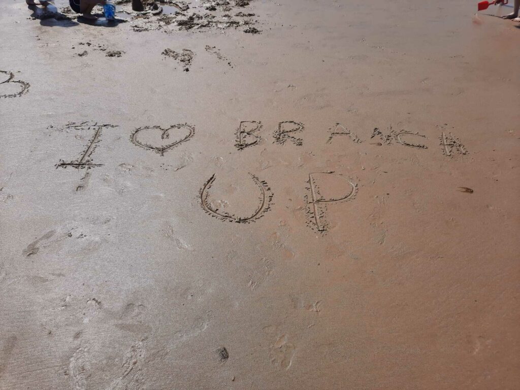 Sandy beach and someone has drawn in "I (heart shape) Branch Up"