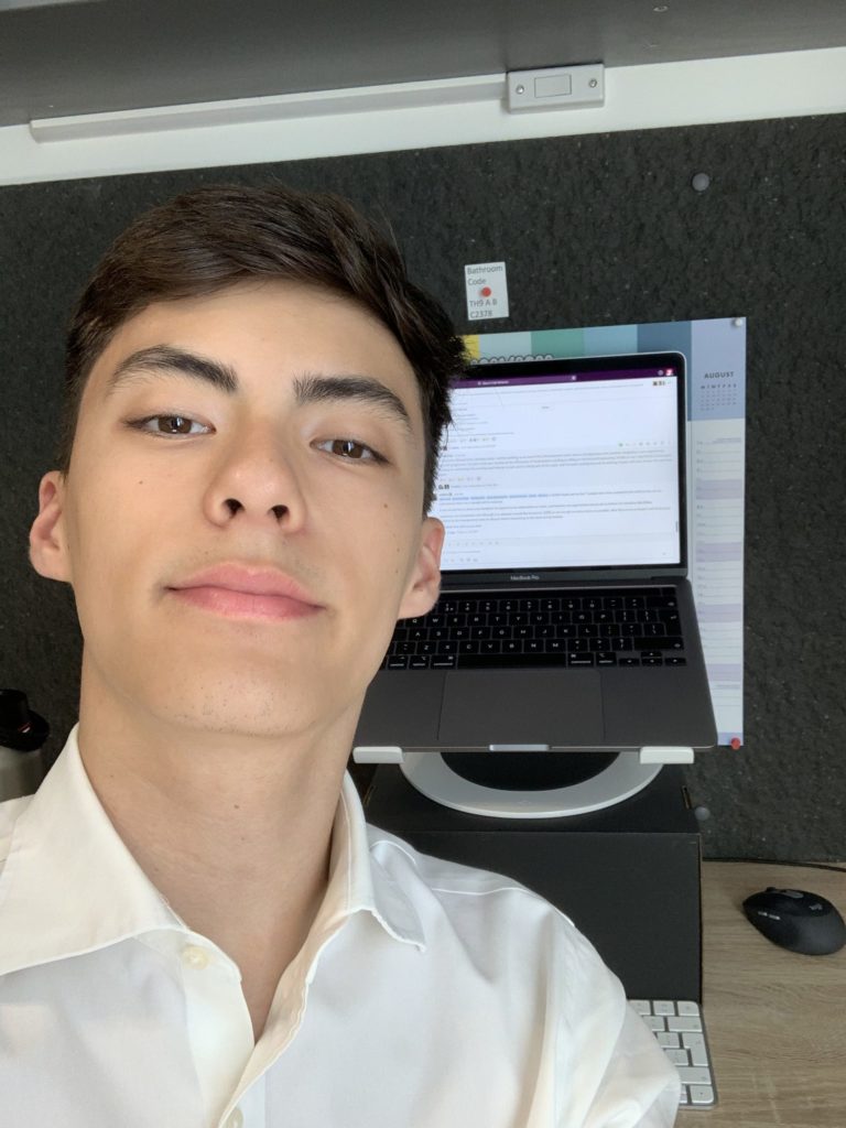 Southampton Hub intern, Michael, smiles at the camera in front of a laptop