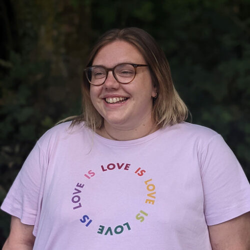 Southampton Hub Manager, Catherine, stands in front of foliage smiling. She is looking slightly to the left.