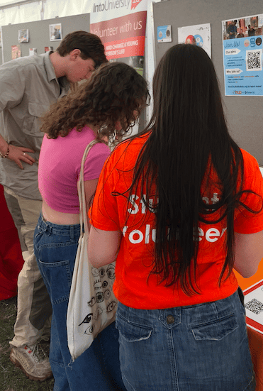 Group of students and volunteers gathered around a tall at Freshers Fayre.