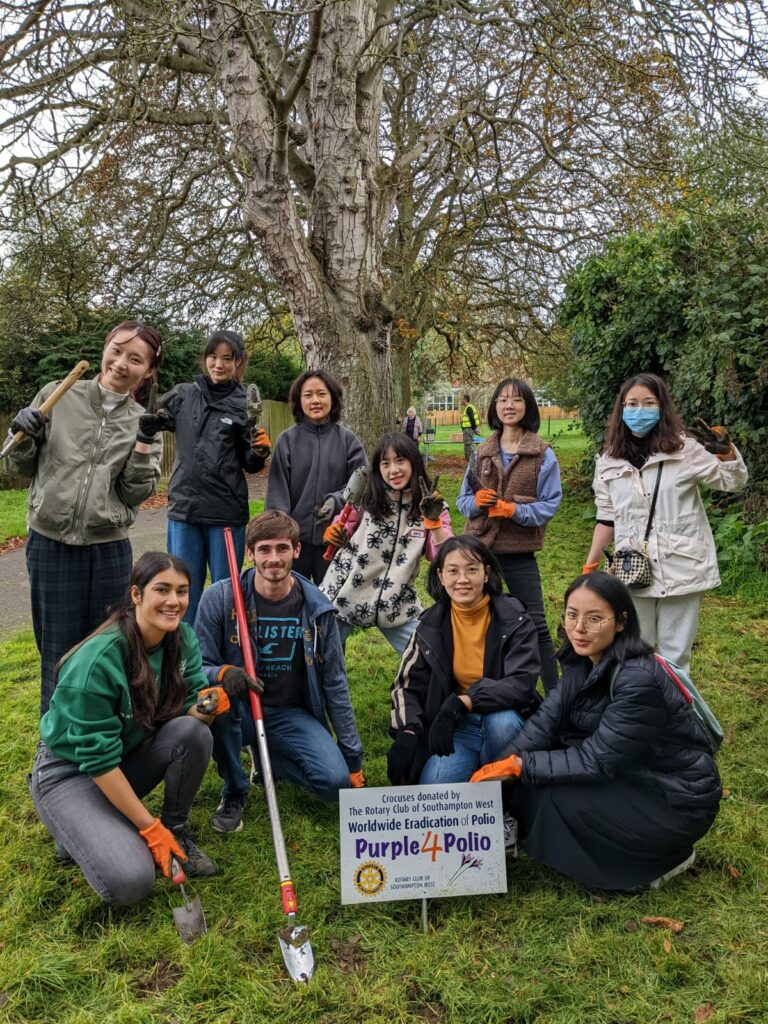 Group of students smiling to the camera holding shovels