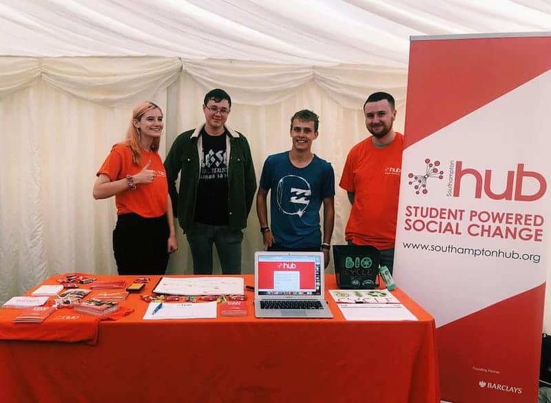 From left to right, Holly, Jordan, Jack and Tom are at the volunteering fayre, behind a table with leaflets on.