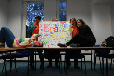 A group photo of Branch Up staff from 2015. Sim and other staff members show off a hand-painted Branch Up sign.