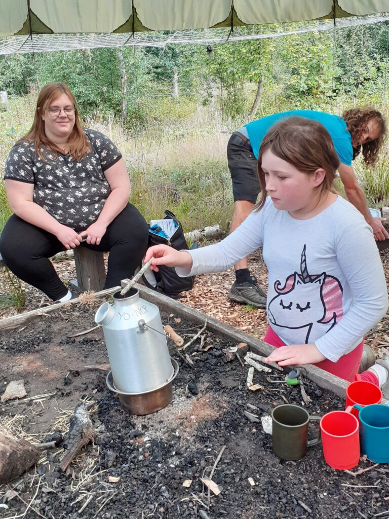 ID: Catherine smiles at a Branch Up participant, who is absorbed in the activity they are doing