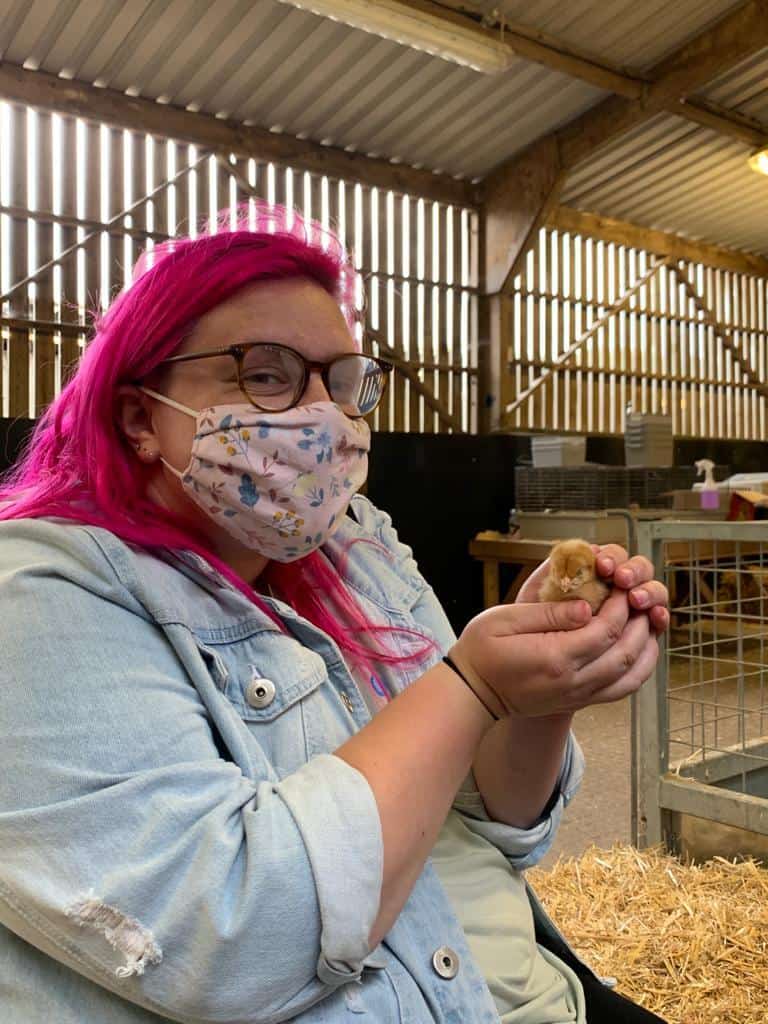ID: Catherine holds a chick in a barn