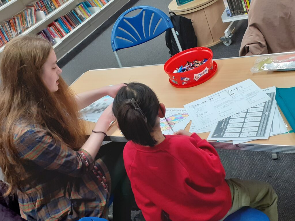 ID: a volunteer works with a child on a homework task